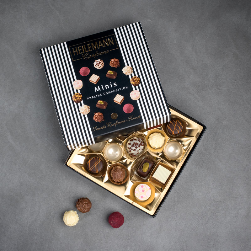 Blick in die geöffnete, schwarze-weiße HEILEMANN Minipralinen Packung mit unterschiedlichen Pralinen
